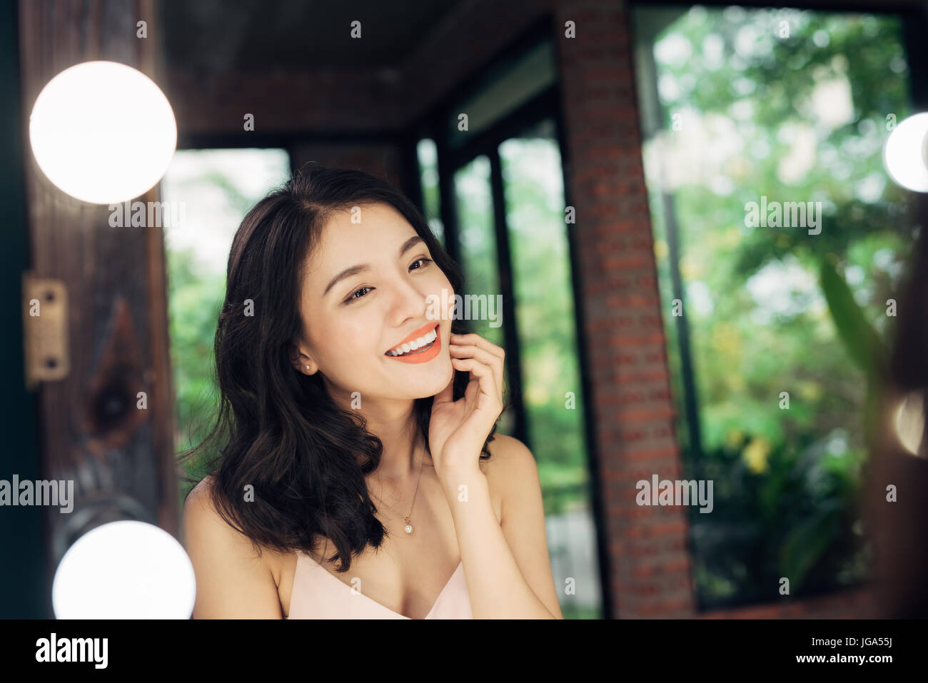 Ziemlich zufrieden asiatische Frau auf sich selbst in einem großen Spiegel zu Hause beobachten. Stockfoto