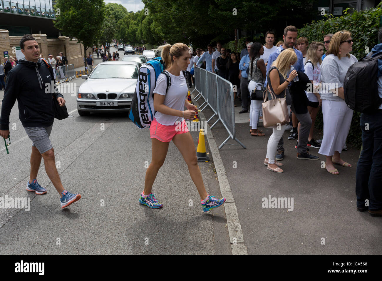 Ein Tennisspieler Dame kreuzt die Straße in der Nähe eine Warteschlange von Zuschauern während der Wimbledon Tennis Championships, 3. Juli 2017, in Wimbledon, London, England. Stockfoto