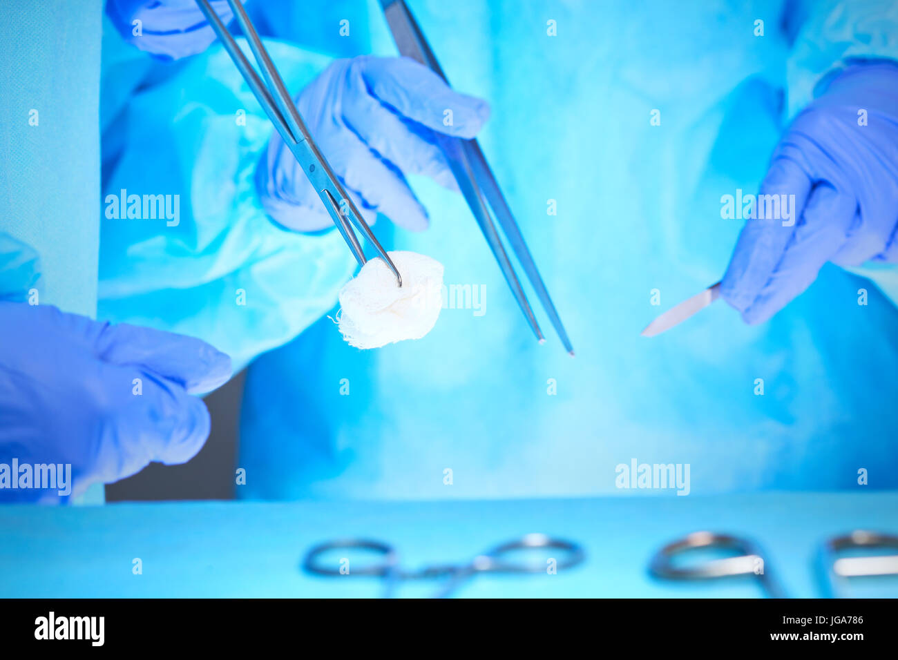 Nahaufnahme des Chirurgen Hände bei der Arbeit im Operationssaal in blau getönt Stockfoto
