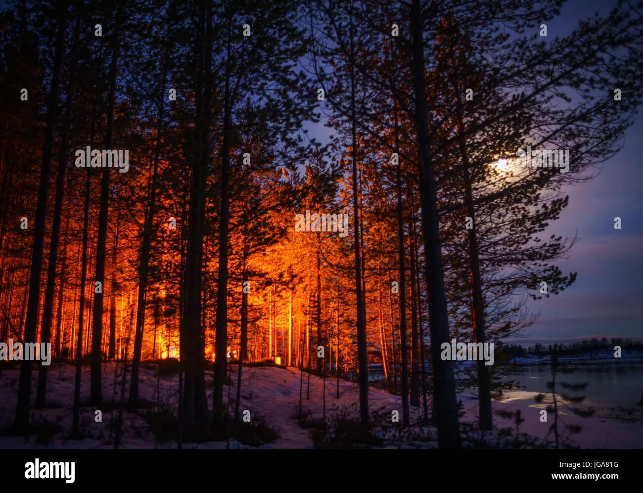 Mondlicht und orange Leuchten von einem Lagerfeuer, Lappland, Finnland Stockfoto