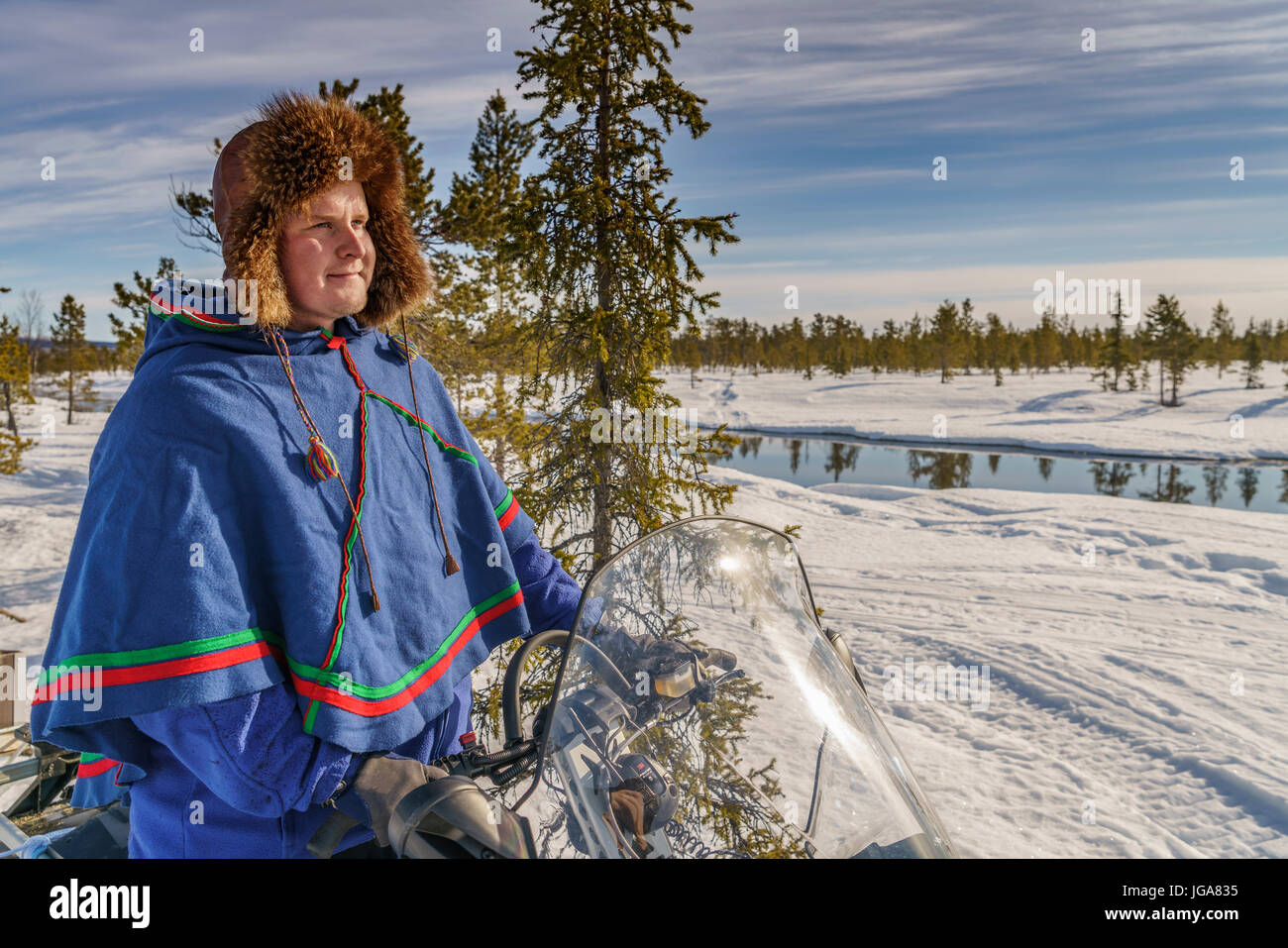 Mann in traditioneller Kleidung der Sami auf einem Schneemobil, Lappland, Schweden Stockfoto