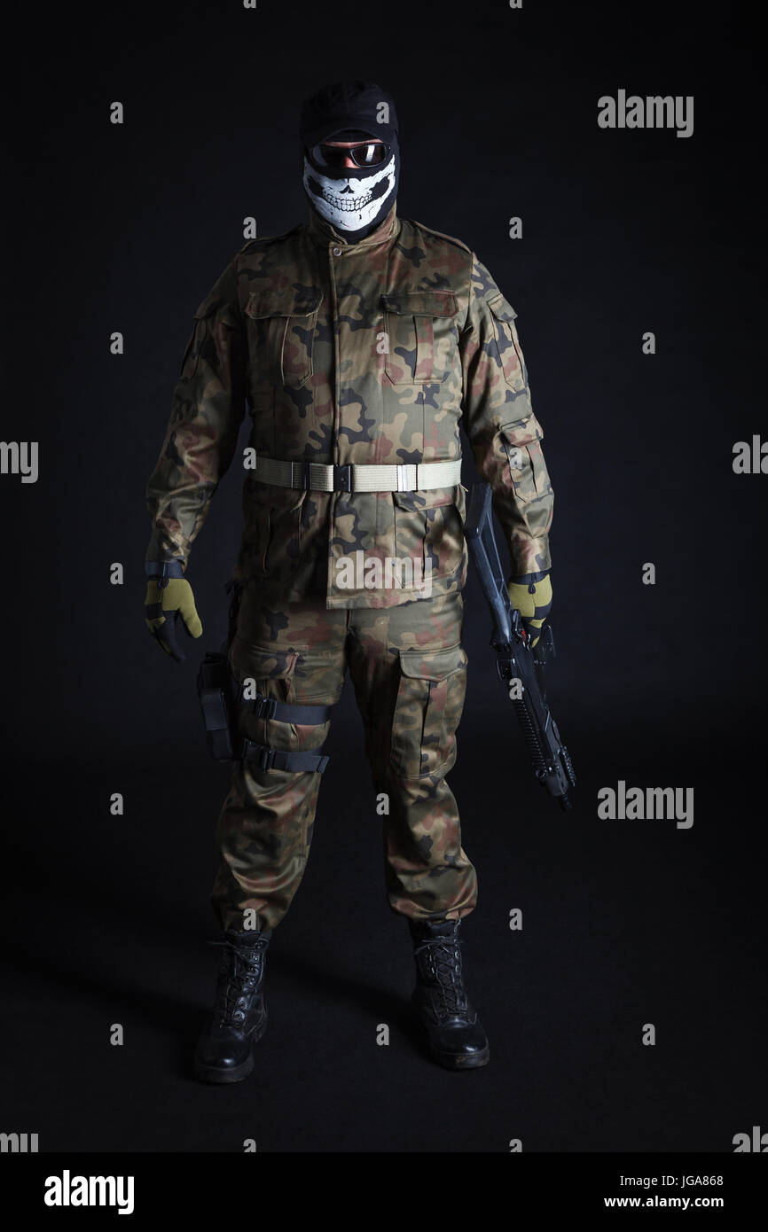 Anti-Terrorist in schwarzer Maske hält eine Pistole auf schwarzem Hintergrund Stockfoto
