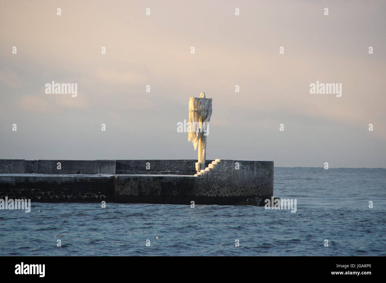 Die Skyline von Eiszapfen auf dem gefrorenen Hafen Lampe auf Pier. Winter am Meer. Stockfoto