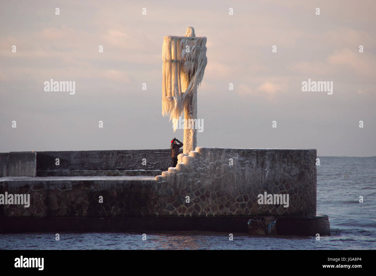 Die Skyline von Eiszapfen auf dem gefrorenen Hafen Lampe auf Pier. Winter am Meer. Stockfoto