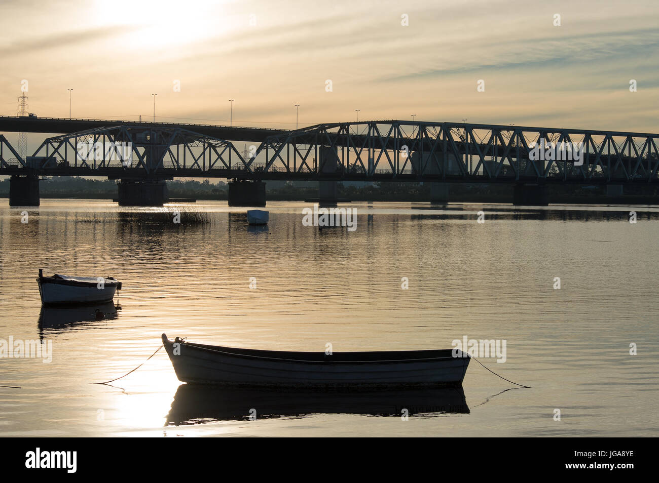 Silhouette der Brücke und Booten über den Fluss Santa Lucia bei Sonnenuntergang in Uruguay Stockfoto