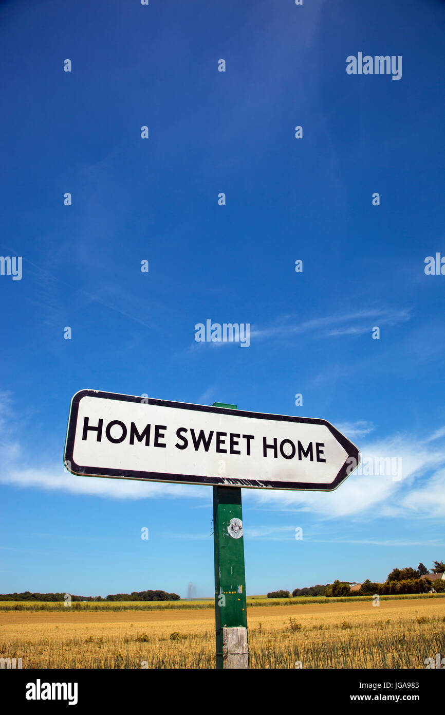 Auf dem Lande ein Verkehrszeichen mit der Aufschrift traute Heim, mit blauem Himmel und einem Feld im Hintergrund Stockfoto