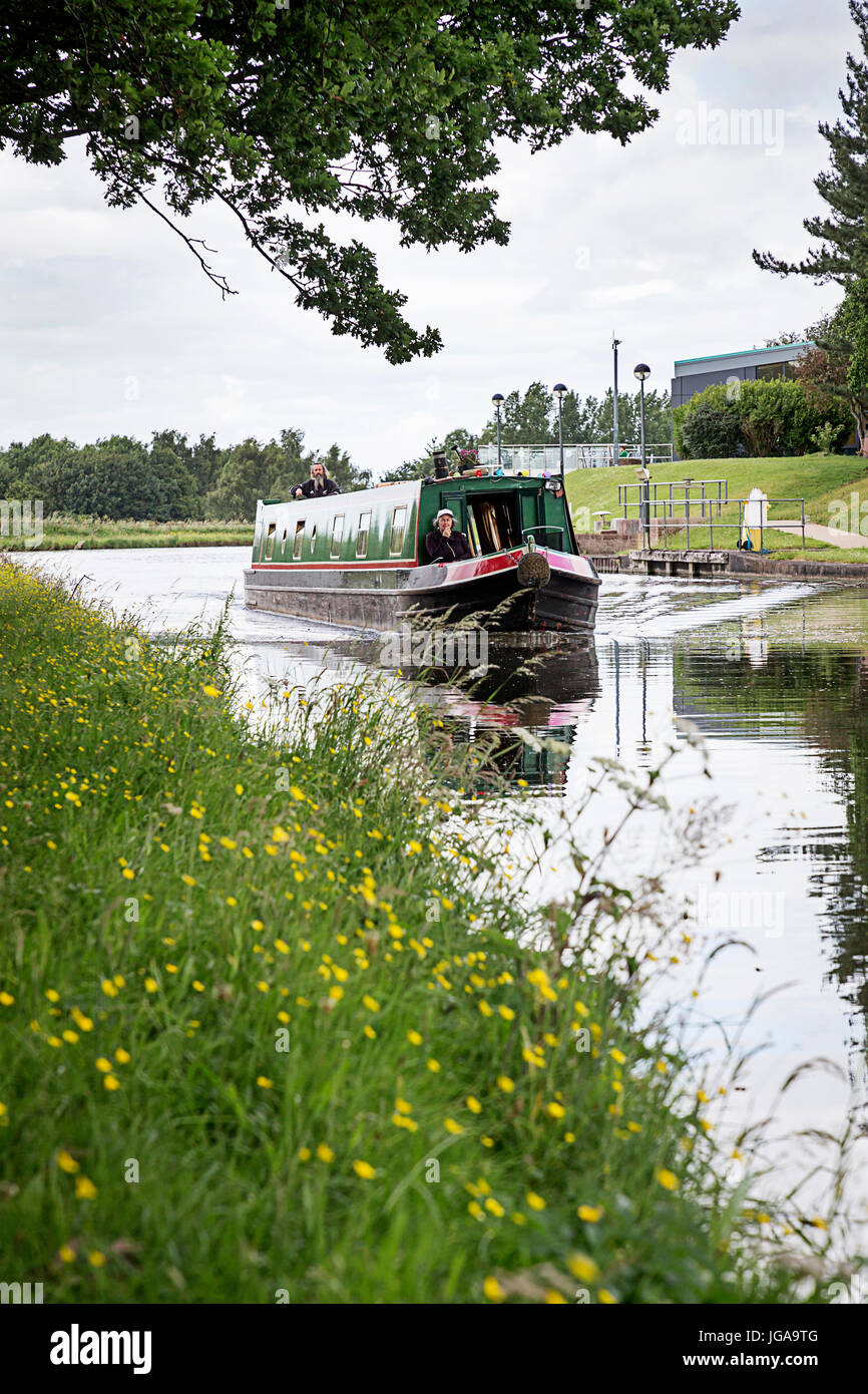 Schmale Boot mit zwei Personen an Bord reisen entlang Bridgewater Kanals in der Nähe von Daresbury internationalen Wissenschafts- und Technologiepark Stockfoto