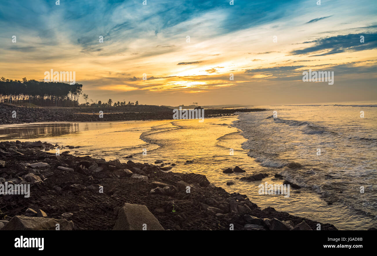 Sonnenaufgang am indischen Strand mit Meer und Felsen und Moody sky Stockfoto