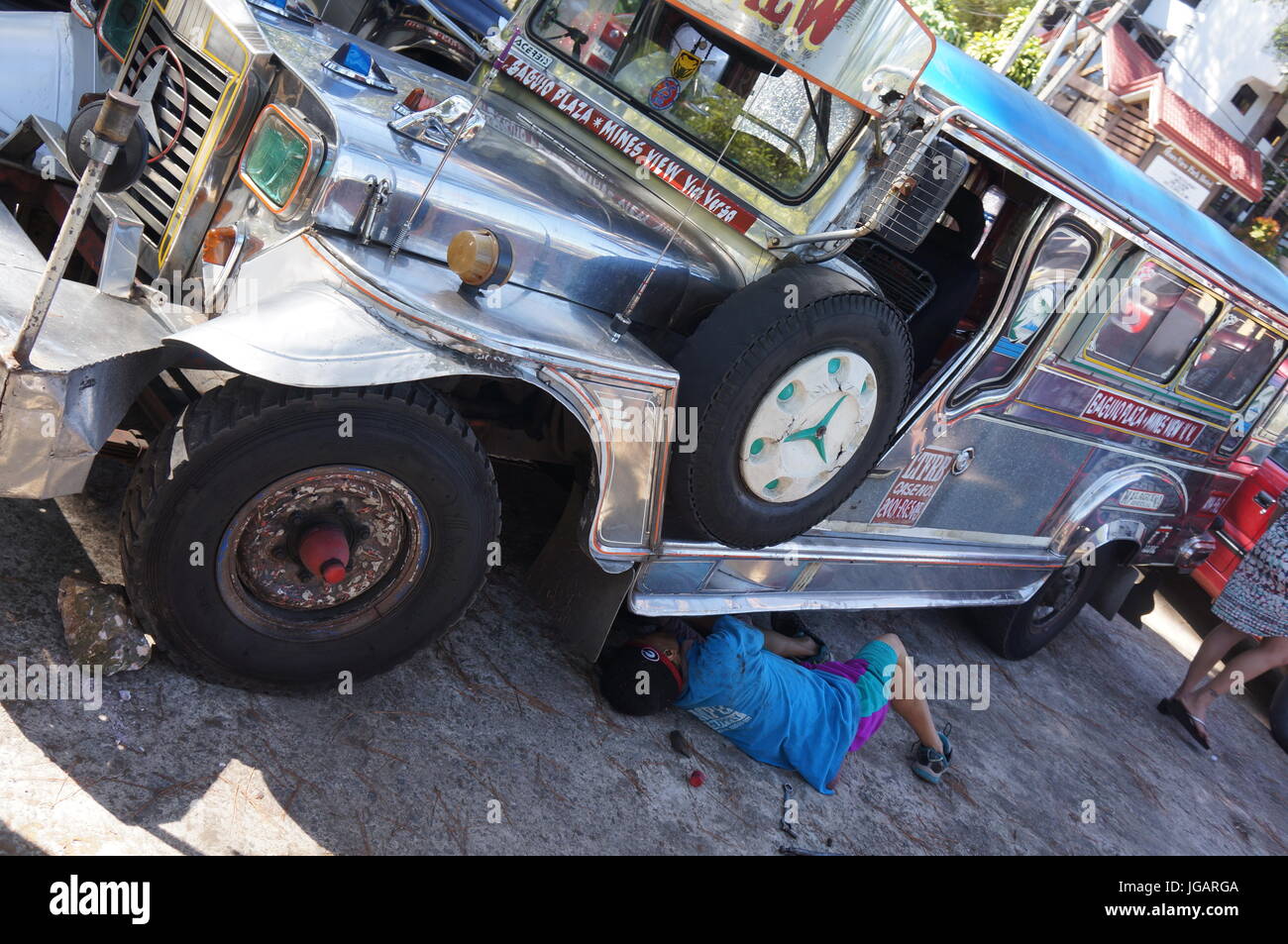 Silber verzierte Jeepney von Mann an sonnigen Tag repariert aufgeschlüsselt.  A umgewandelt Jeep Dies ist eine gemeinsame öffentliche Verkehrsmittel in Philippinen, Baguio. Stockfoto