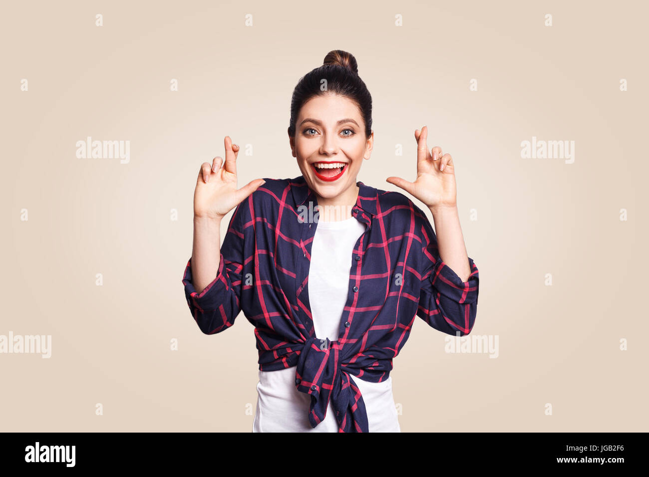 Porträt von schönen Mädchen in lässigen Stil, Blick in die Kamera mit Lügner Pose lachen. Studio auf Beige Hintergrund gedreht. Stockfoto