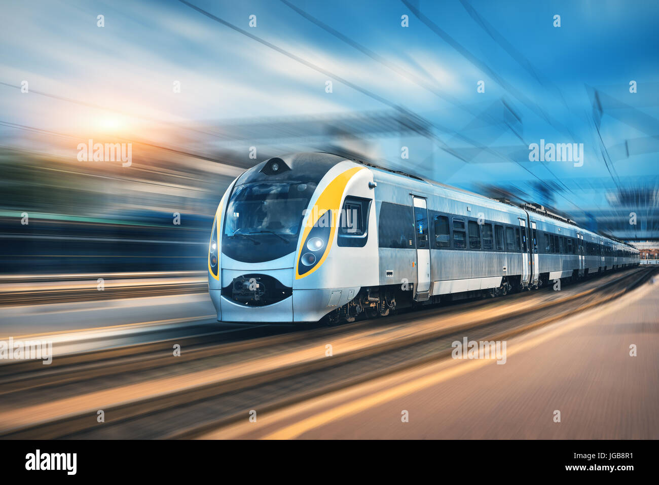 High-Speed-Zug in Bewegung am Bahnhof bei Sonnenuntergang in Europa. Modernen intercity Zug auf dem Bahnsteig mit Motion-Blur-Effekt. Leichtbauteile Stockfoto