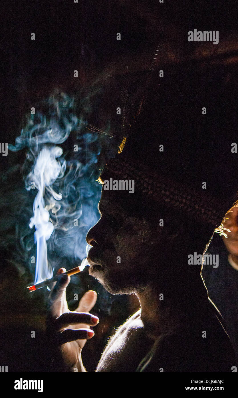 Indonesien, IRIAN JAYA, ASMAT Provinz, JOW Dorf - Juni 12: Asmat Stamm Mann raucht in der Dunkelheit. Stockfoto