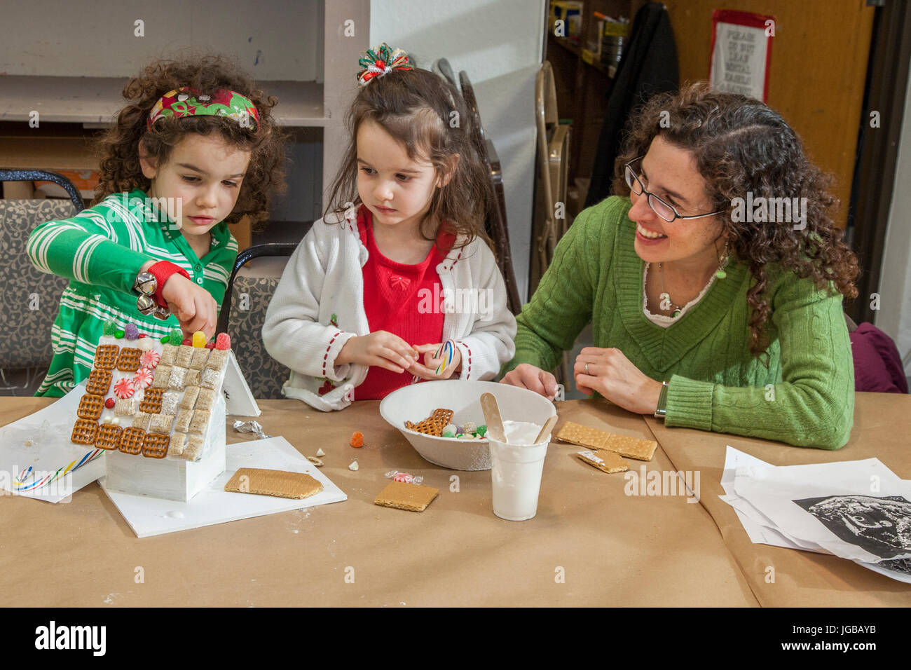 Eine Frau, die kleinen Kindern mit einem Kunstprojekt hilft Stockfoto