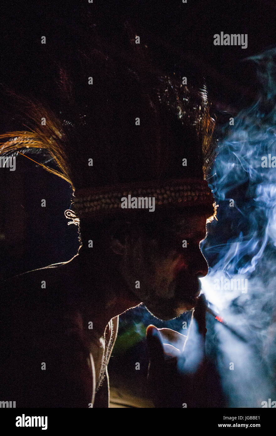Indonesien, IRIAN JAYA, ASMAT Provinz, JOW Dorf - Juni 12: Asmat Stamm Mann raucht in der Dunkelheit. Stockfoto