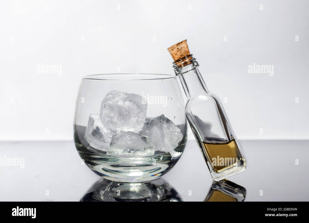 Kleine Miniatur korkigen Whisky-Flasche und ein Whiskeyglas mit Eis Stockfoto