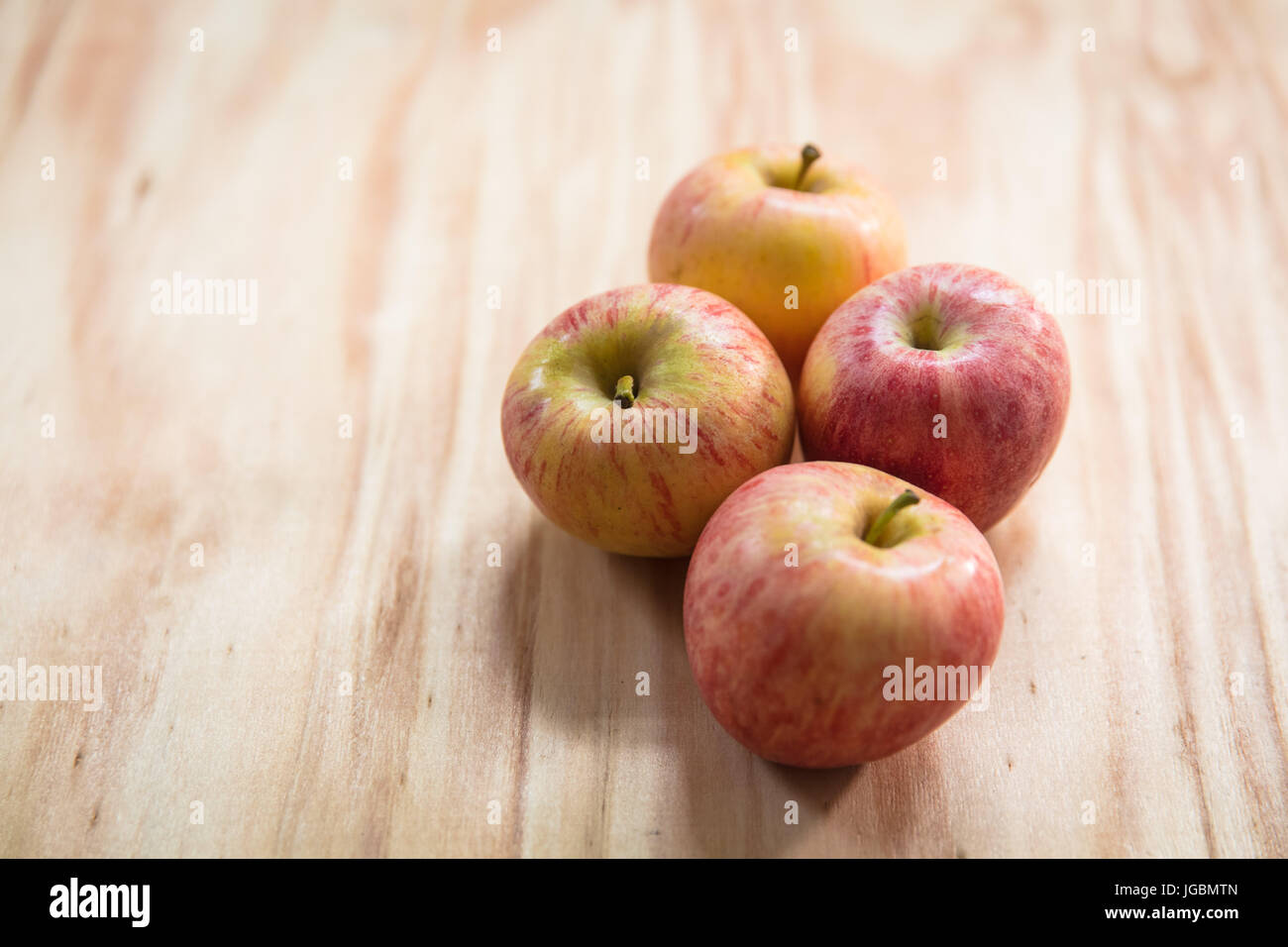 Vier Äpfel auf einer Holzfläche.  Pink Lady-Vielfalt Stockfoto