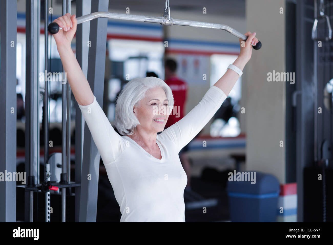 Lächeln alte Dame arbeitet am Fitnessgerät Stockfoto