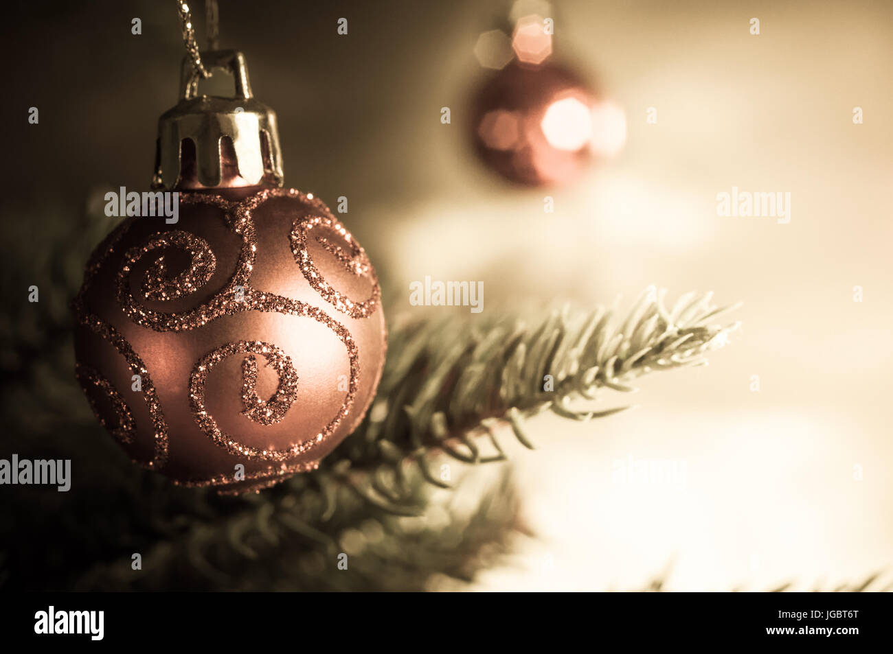 Nahaufnahme von einer hängenden Chistmas Baum Christbaumkugel mit Glitzer Glitzer Swills mit Weihnachtsbaum Äste und eine weitere Kugel in soft-Fokus Backg gemustert Stockfoto