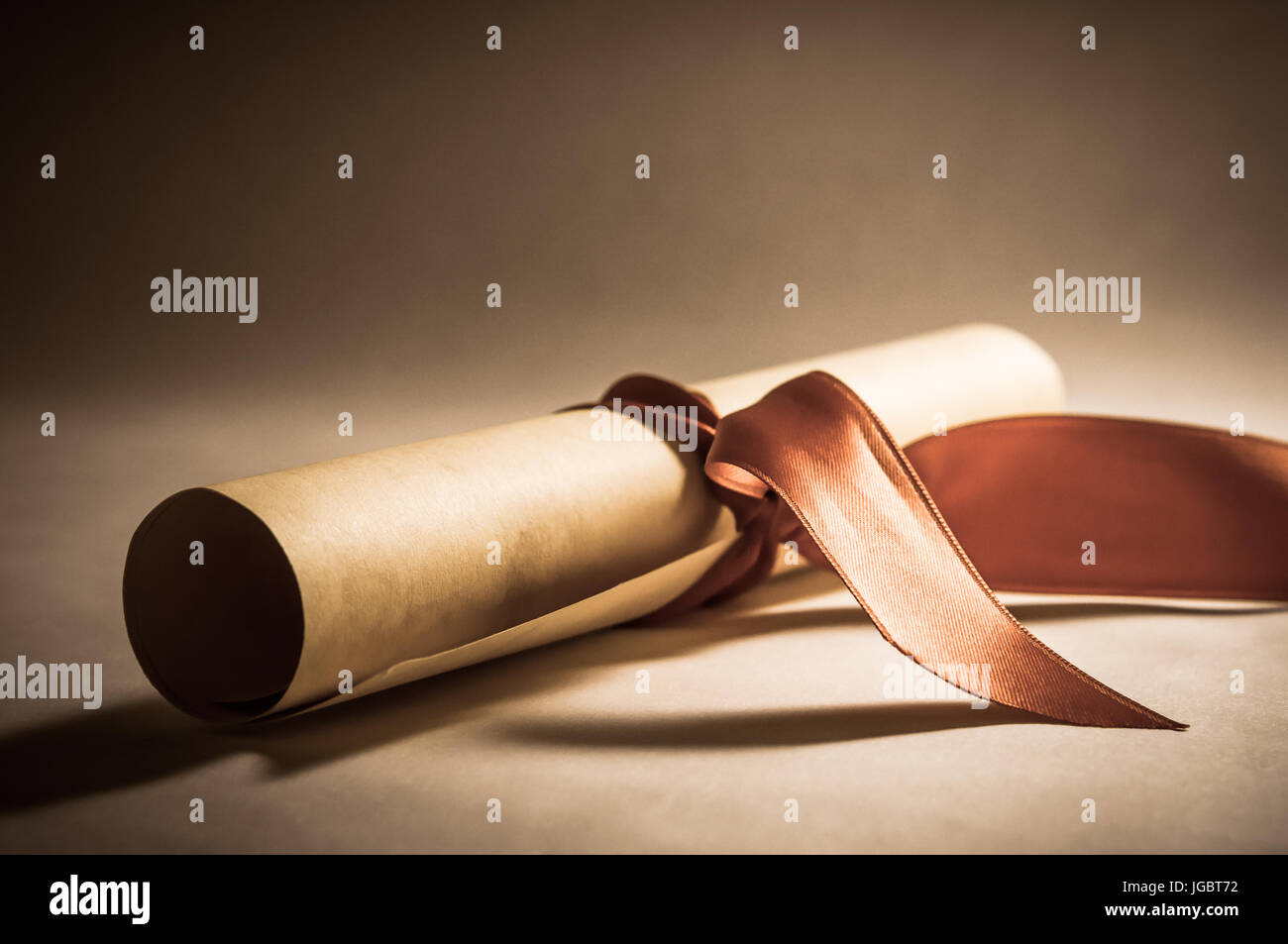 Eine Pergament-Diplom-Schriftrolle, aufgerollt, mit rotem Band schräg gelegt.  Verarbeitet, um eine Vintage oder Retro-aussehen zu geben. Stockfoto