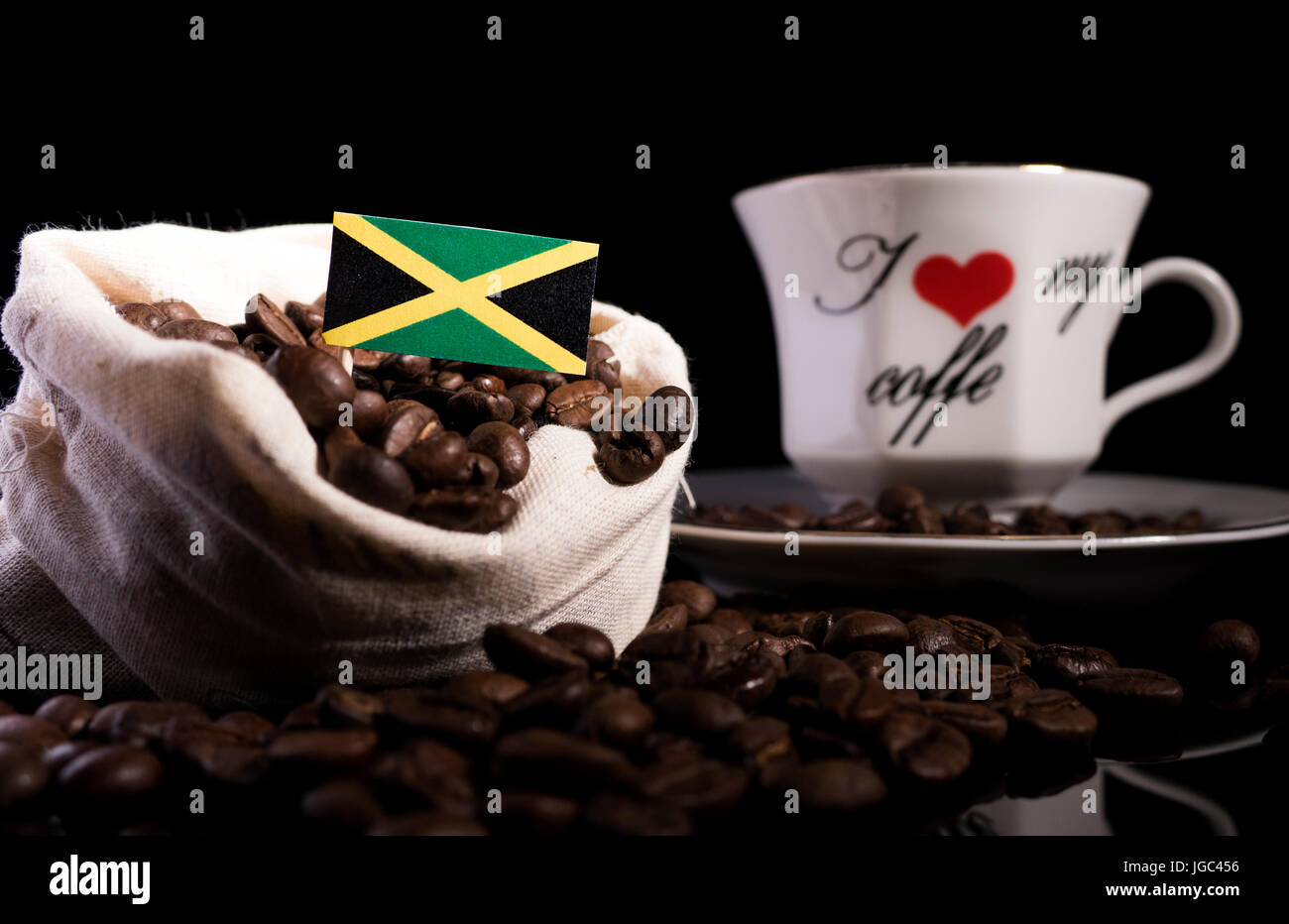 Jamaikanische Flagge in einer Tasche mit Kaffeebohnen auf schwarzem Hintergrund isoliert Stockfoto
