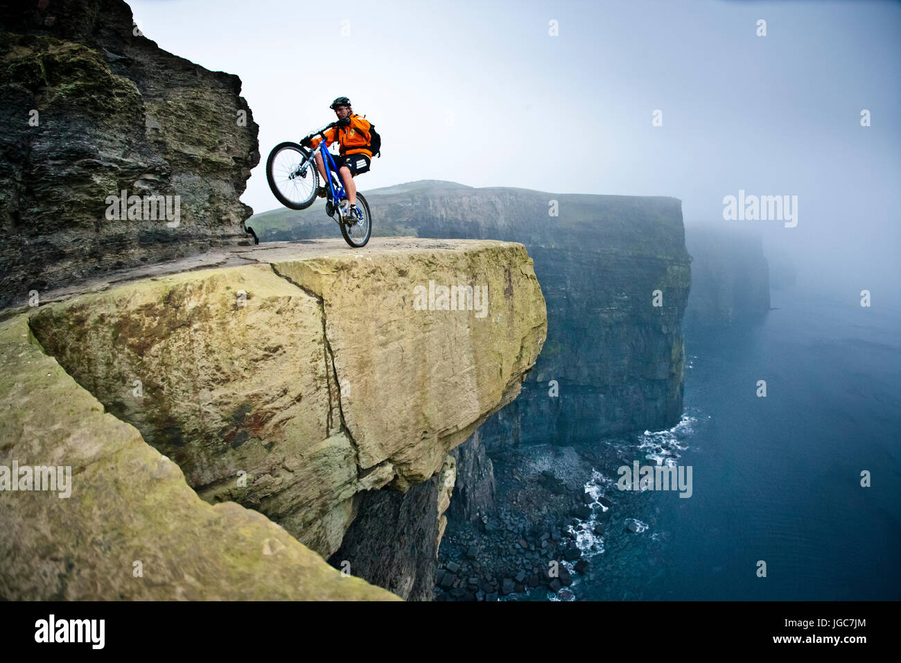 Professionelle Mountainbiker Hans Rey zieht einen Wheelie neben den Cliffs of Moher Stockfoto