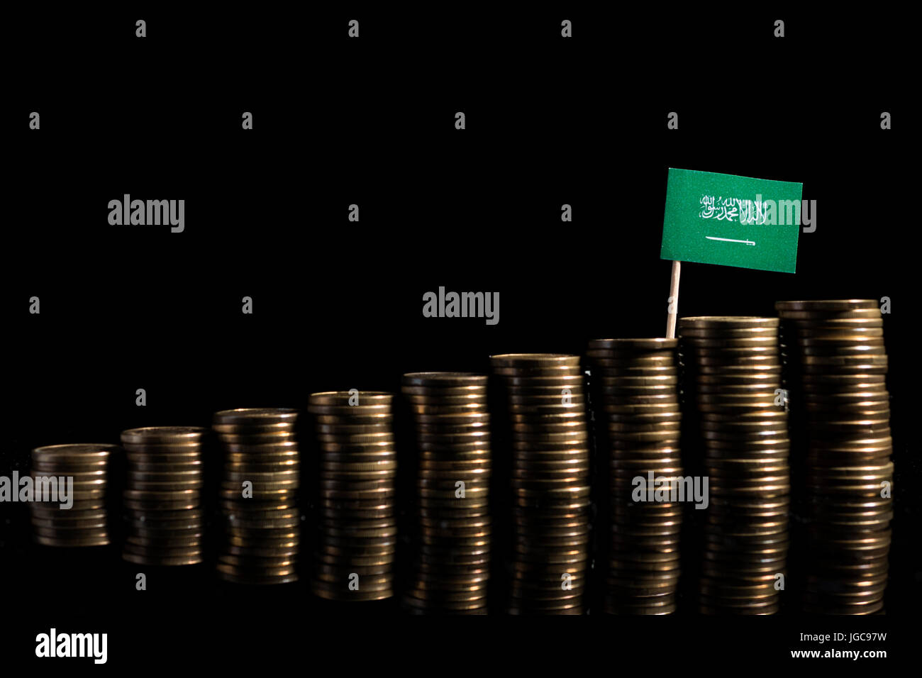 Saudi-Arabische Flagge mit Menge von Münzen auf schwarzem Hintergrund isoliert Stockfoto