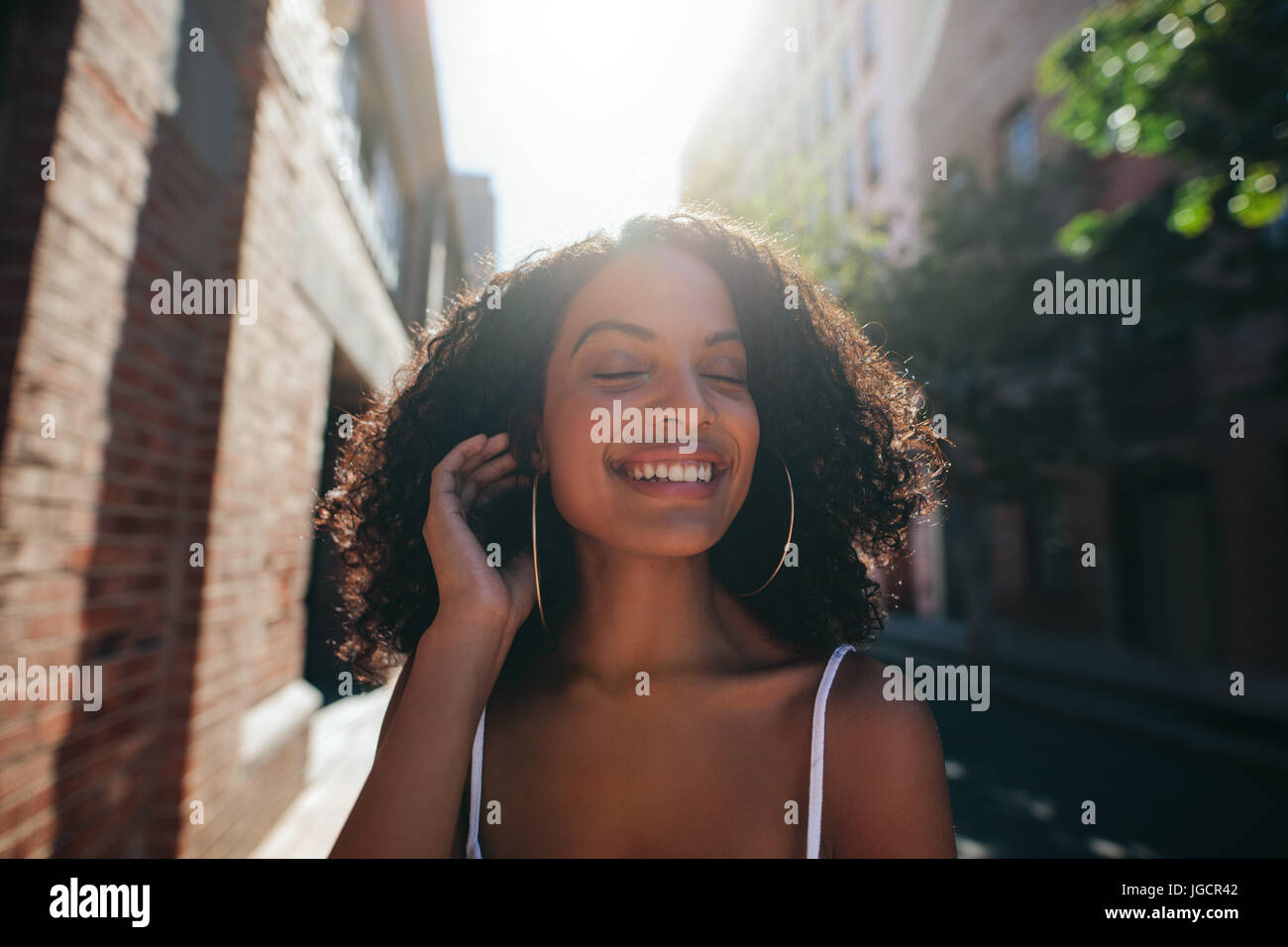 Porträt von schöne junge afrikanische Frau walking im Freien Stadt mit geschlossenen Augen hautnah. Afro american weiblich walking im Freien und lächelnd. Stockfoto