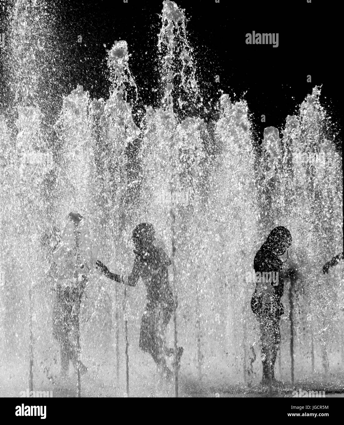 Silhouette der drei Kinder in einem Springbrunnen spielen Stockfoto