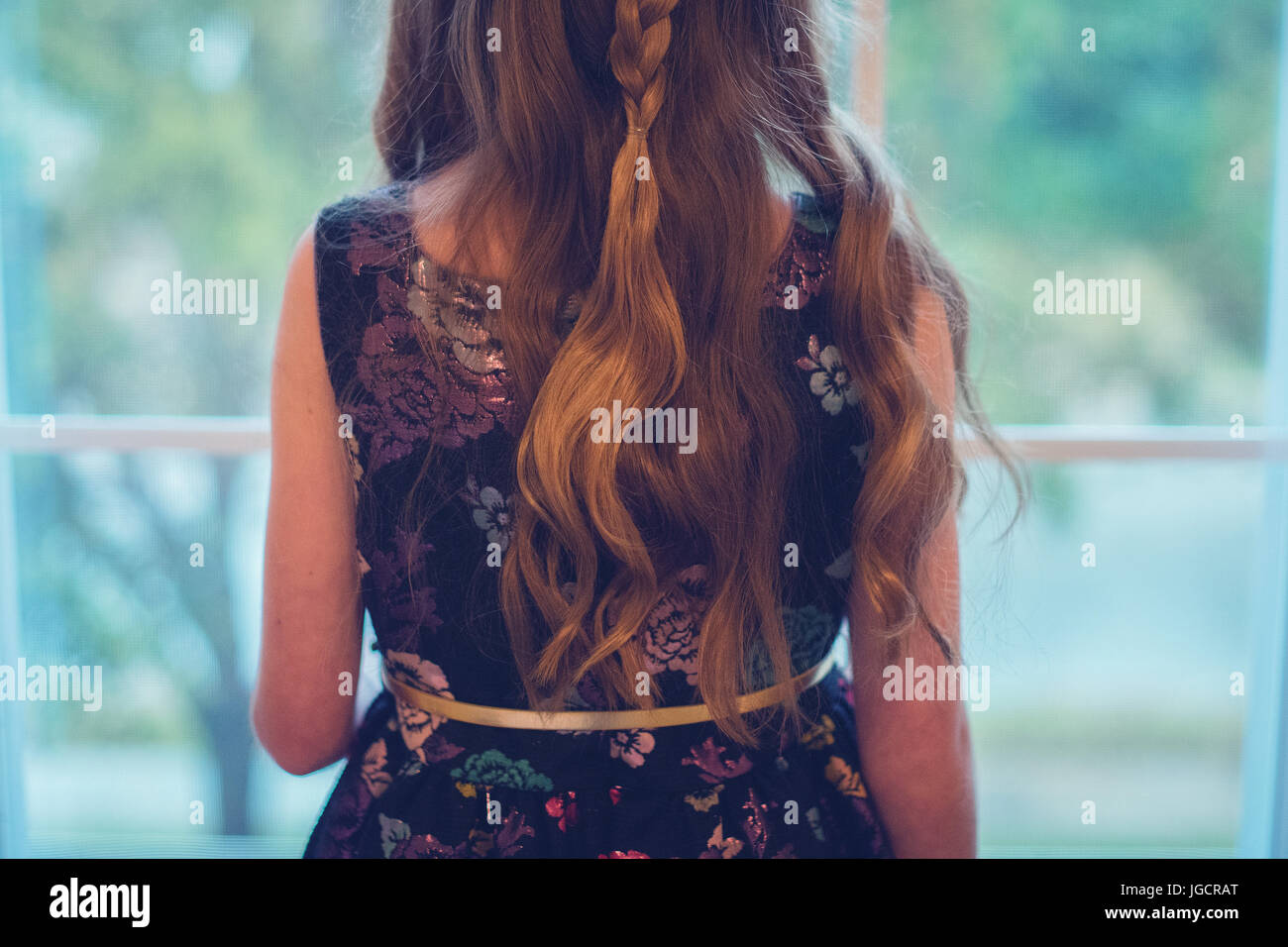 Rückansicht eines Mädchens in einem Partykleid Blick aus einem Fenster Stockfoto