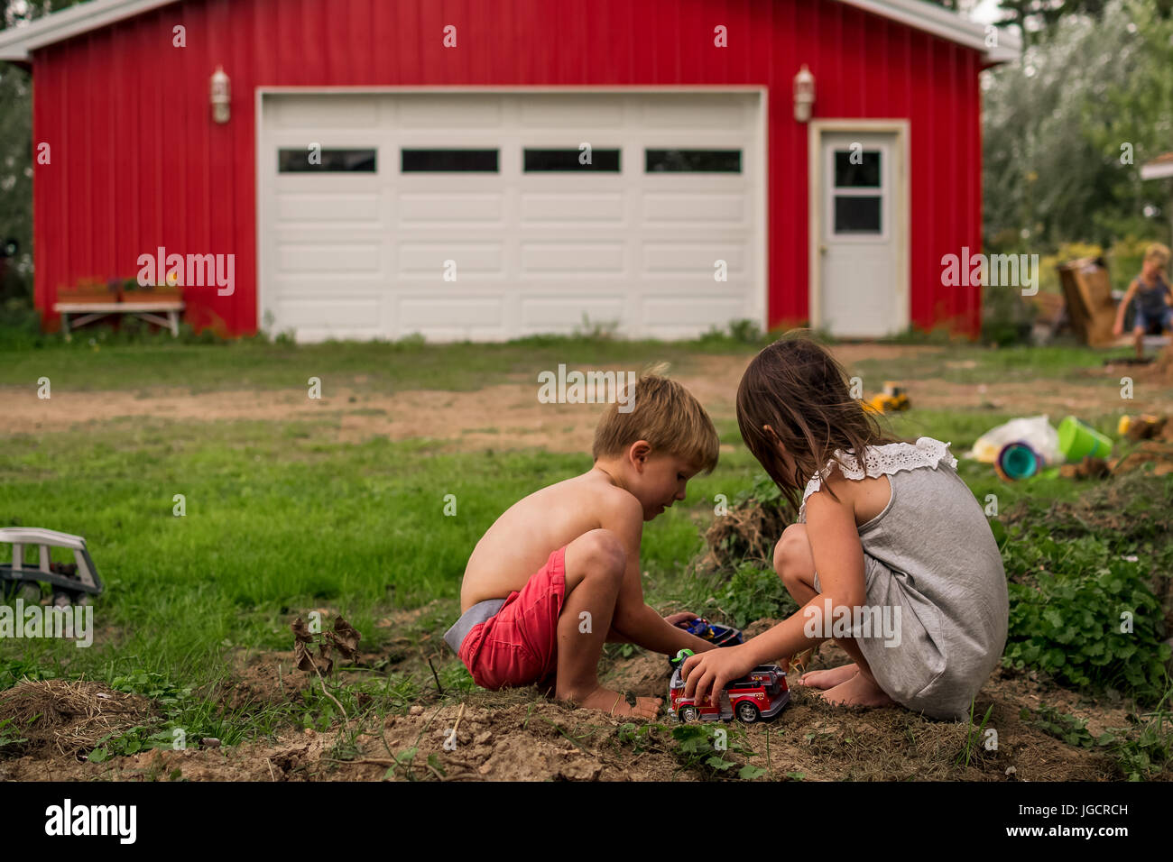Jungen und Mädchen spielen im Dreck mit einem jungen im Hintergrund Stockfoto