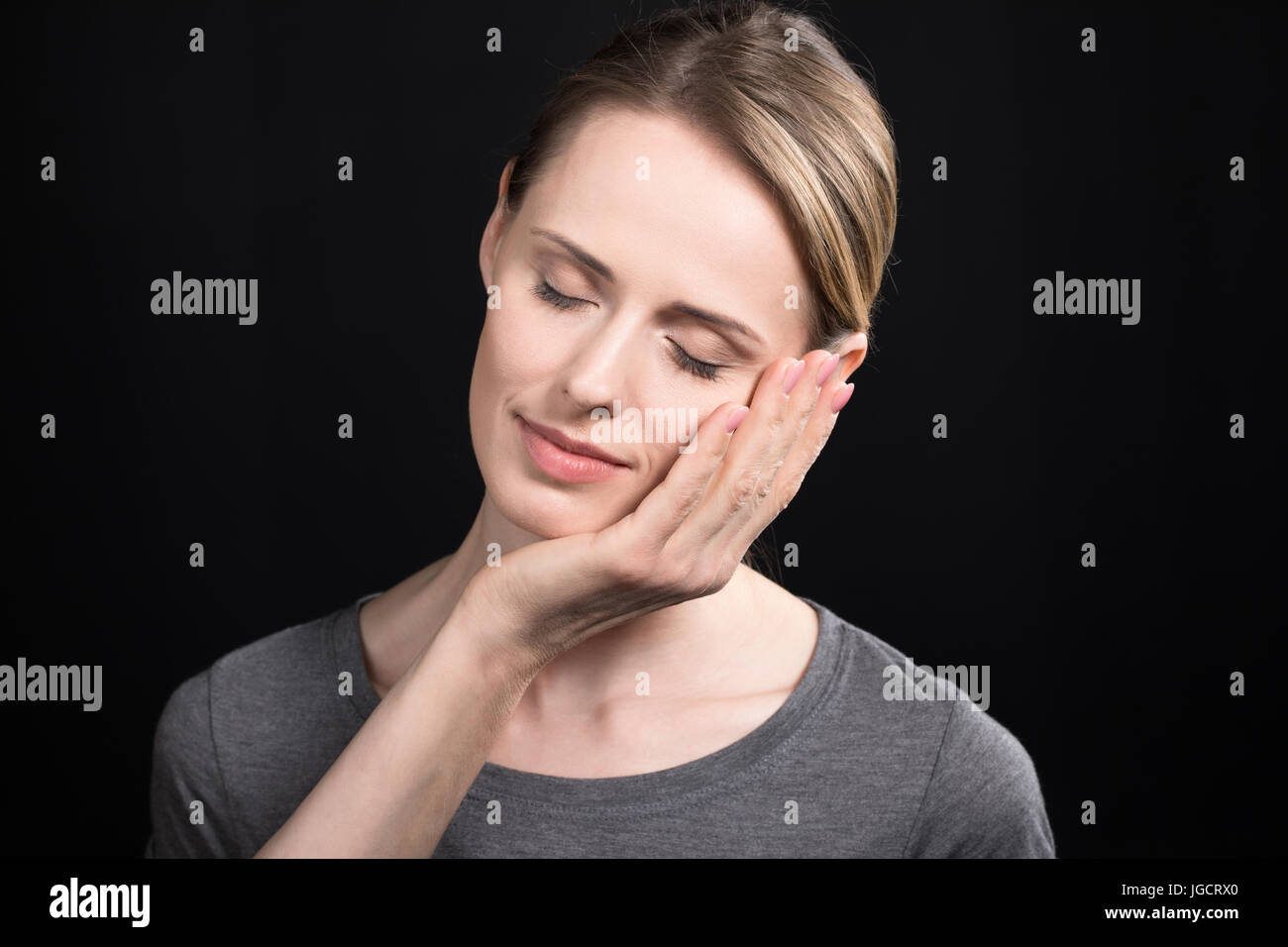 Händen der Mutter junge Erwachsene Tochter Gesicht isoliert auf schwarz Stockfoto