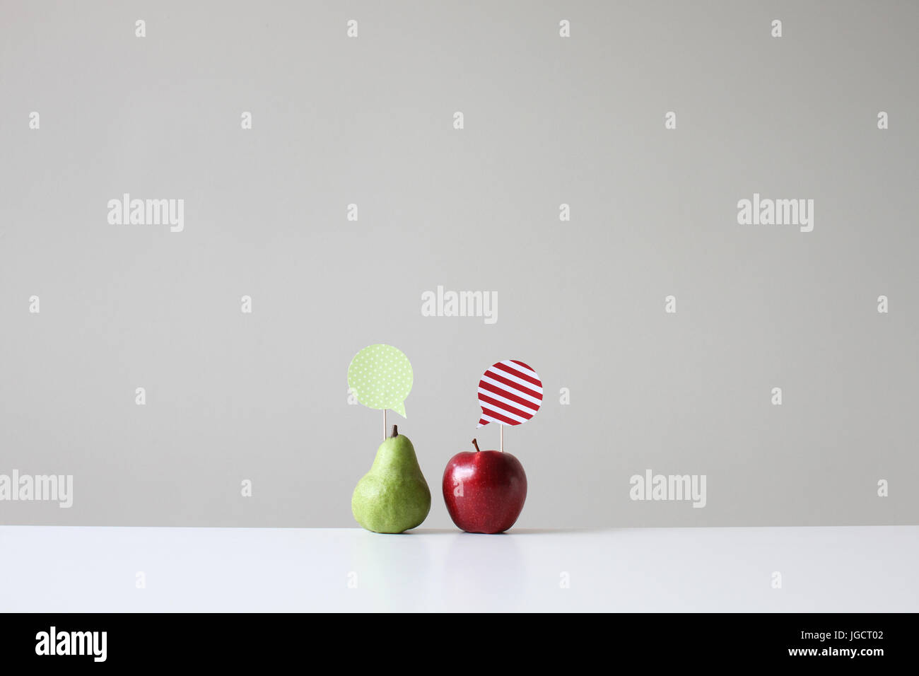 Konzeptionelle Apfel und Birne mit Sprechblasen Stockfoto