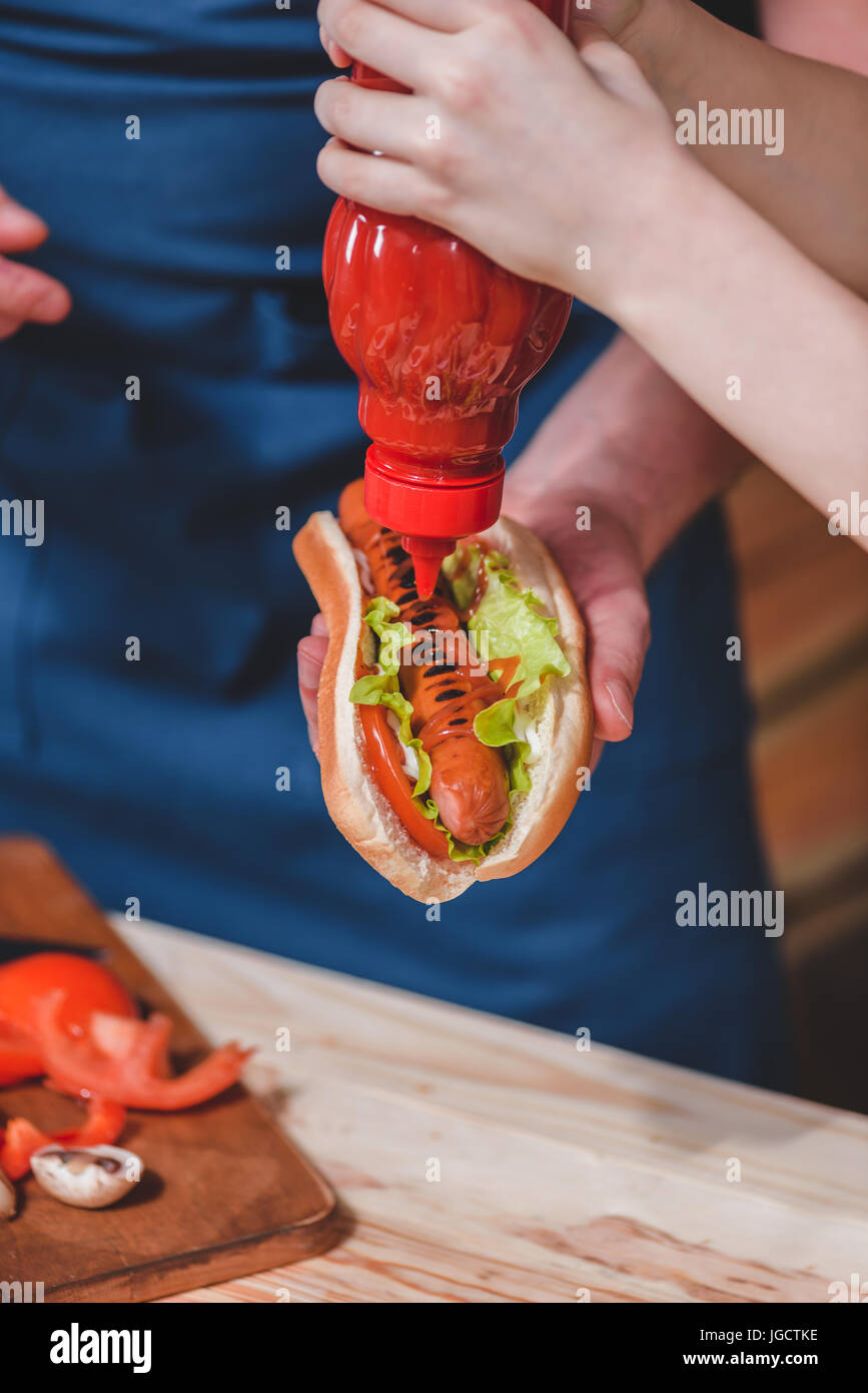Close-up Teilansicht von Vater und Sohn mit Ketchup vorbereiten, hot Dog, Vater und Sohn Kochen Konzept Stockfoto