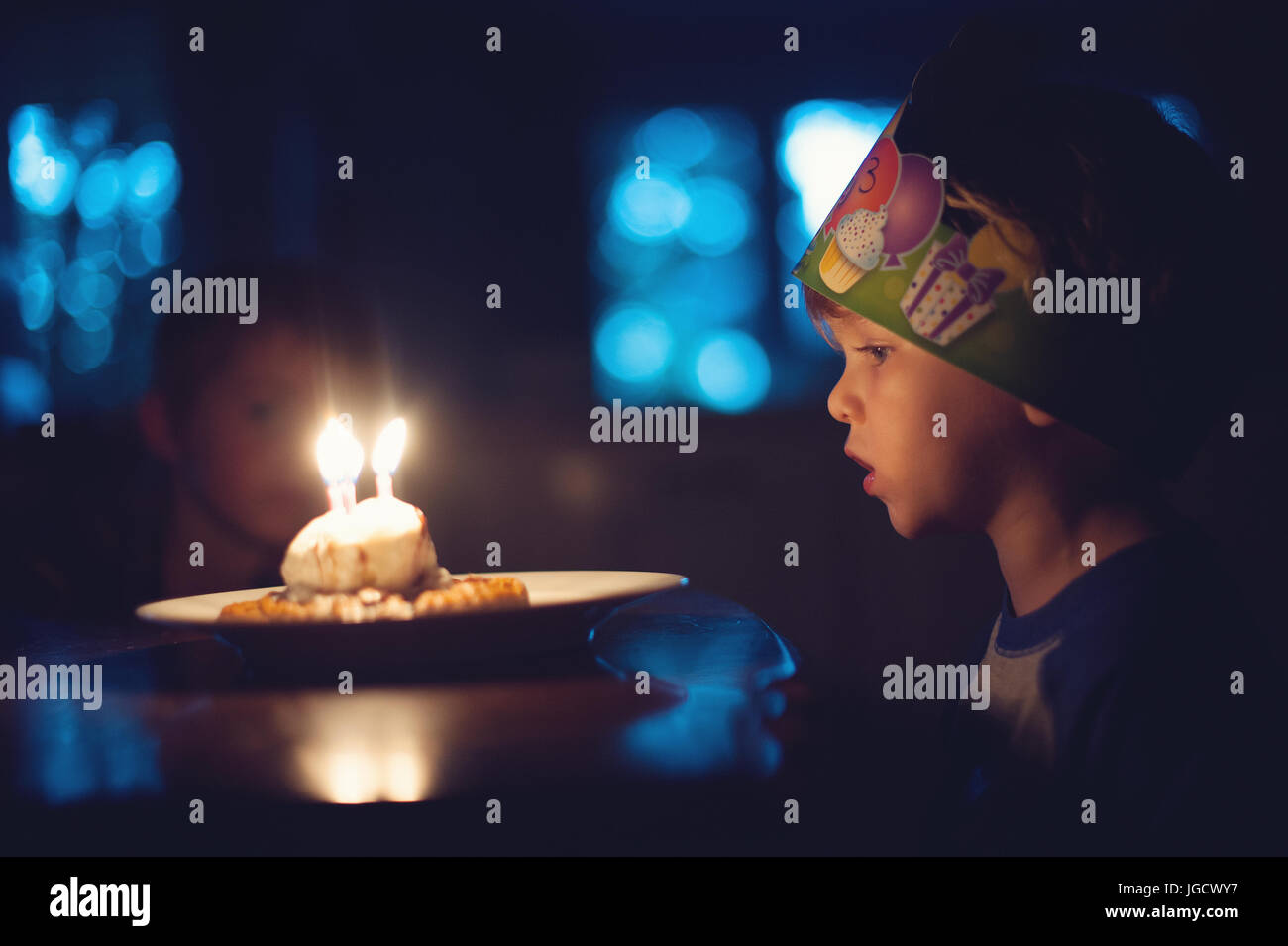 Junge Ausblasen der Kerzen auf seine Geburtstagstorte Stockfoto