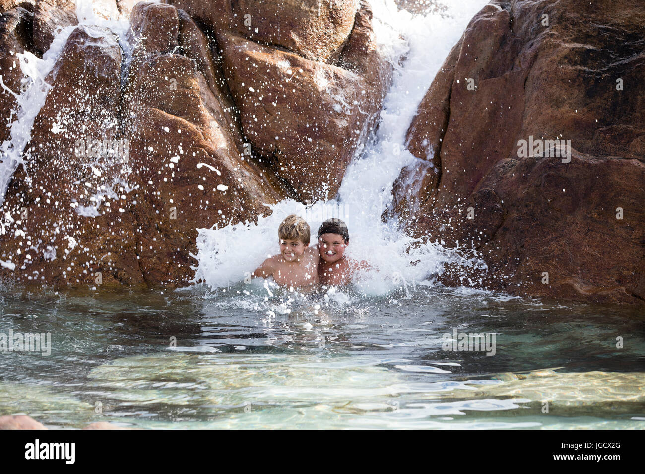 Zwei Jungs spielen in einem Wasserfall, Western Australia, Australien Stockfoto