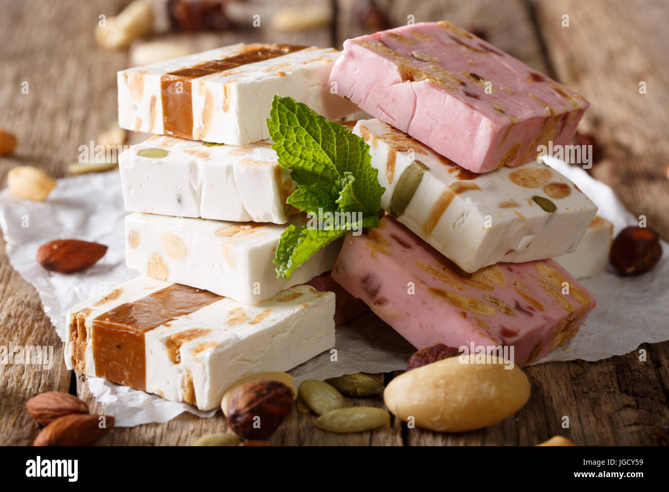 Weiß, rosa und braun Nougat mit Nüssen und Minze Closeup auf dem Tisch. Horizontal, rustikal Stockfoto