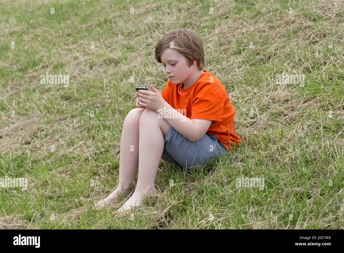 kleiner Junge spielt mit seinem Handy Stockfoto