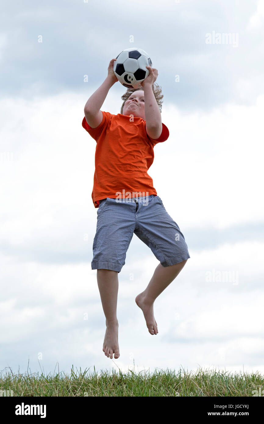 Junge, springen, um einen Ball fangen Stockfoto