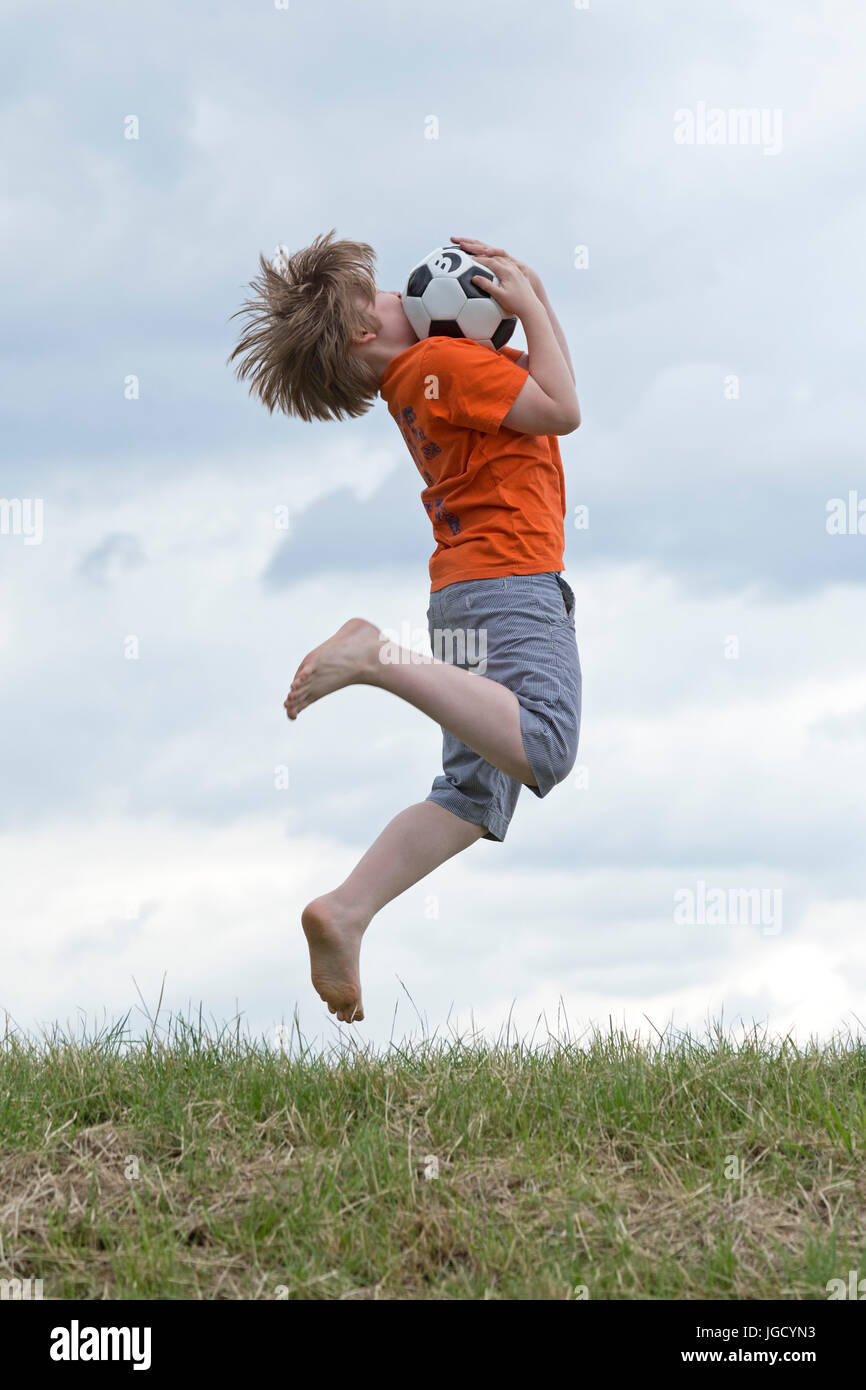 Junge, springen, um einen Ball fangen Stockfoto