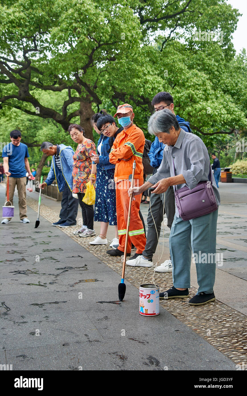 Nationalpark West Lake Hangzhou China, ältere Menschen, die auf dem Bürgersteig mit langen Pinseln schreiben Stockfoto