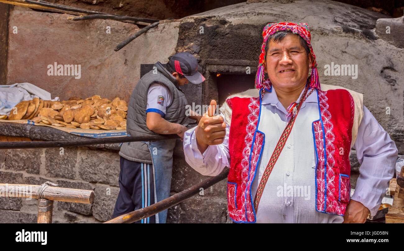 Pisac Peru Mann trägt einen bunten chollo backt Empanadas in einem alten horno Ofen in Peru, Südamerika. Stockfoto
