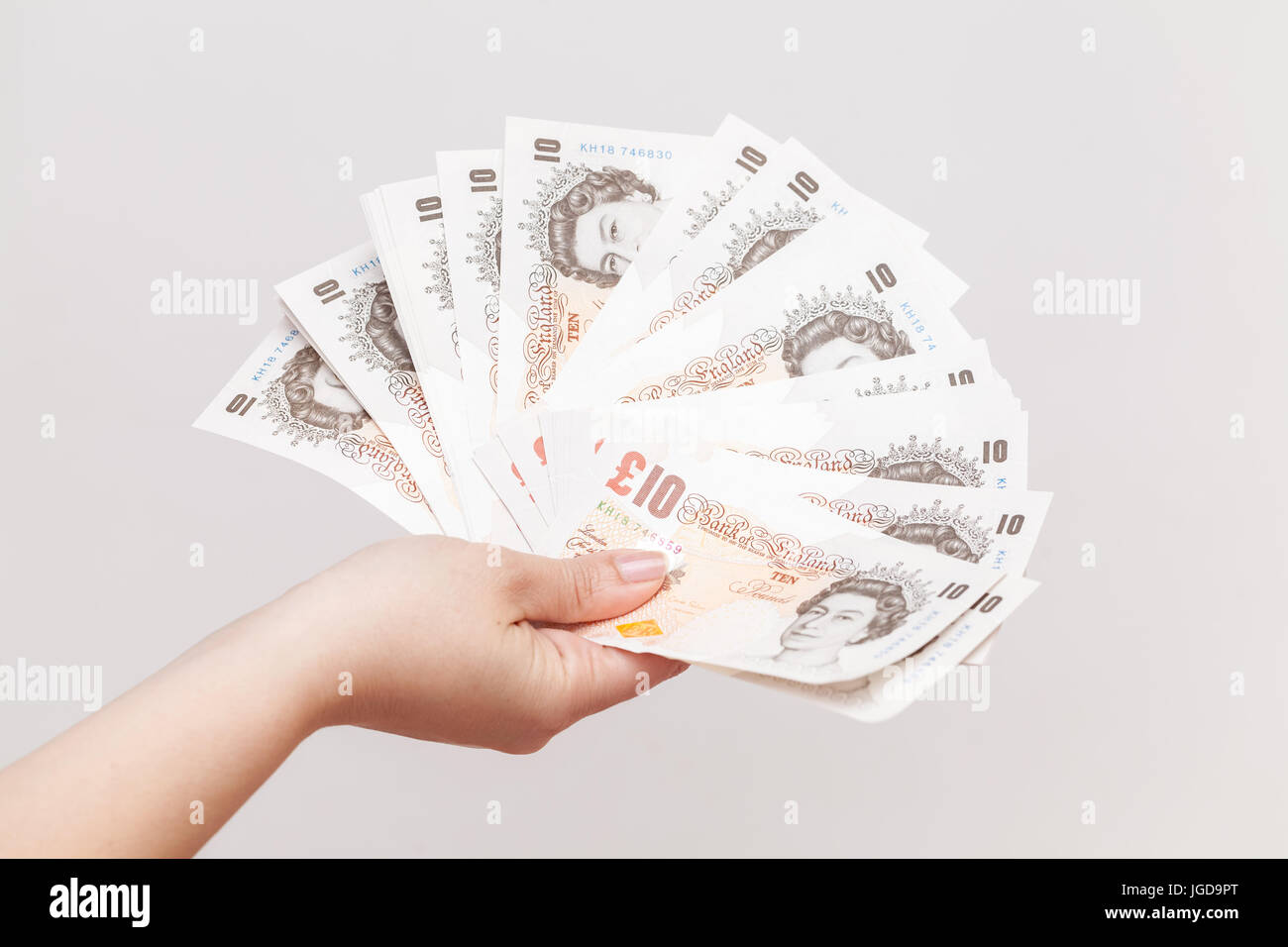 Zehn Pfund-Noten der Bank von England in weiblicher Hand. Nahaufnahme Foto über graue Wand Hintergrund mit selektiven Fokus Stockfoto