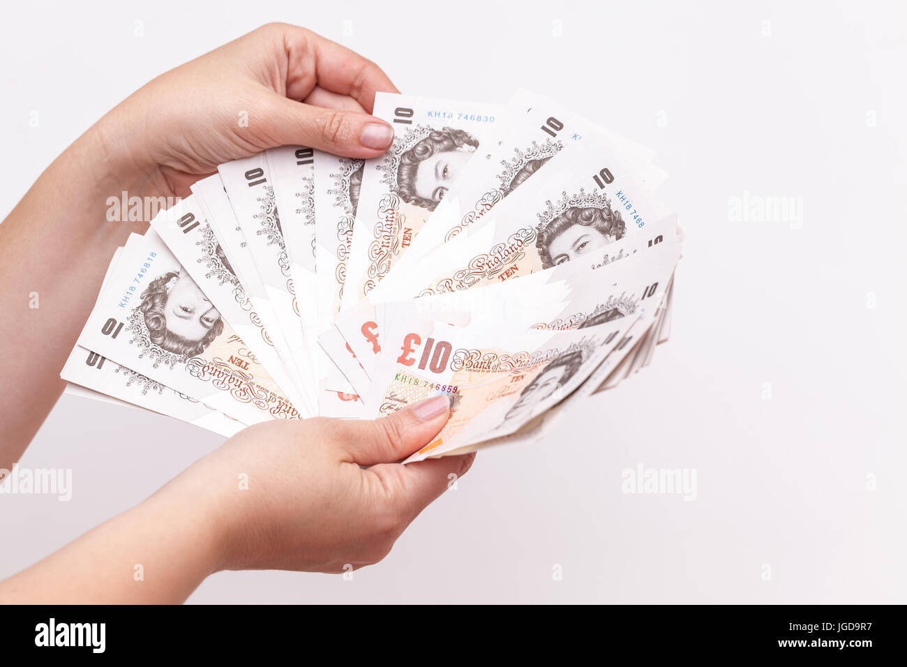 Zehn Pfund Noten der Bank von England in weiblichen Händen. Nahaufnahme Foto über graue Wand Hintergrund mit selektiven Fokus Stockfoto