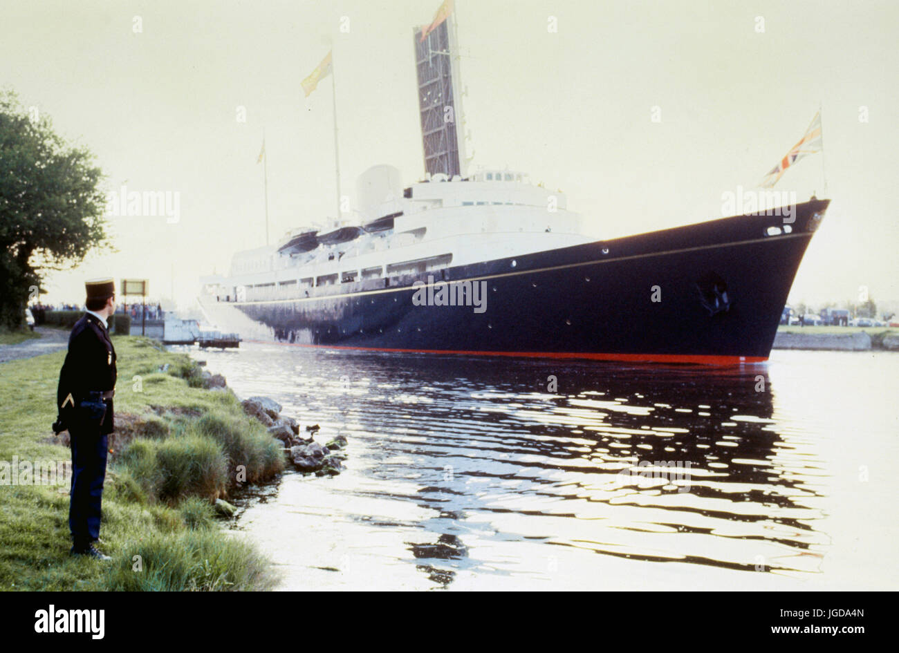 Ein Gendarm Uhren die Royal Yacht Britannia, als es durchläuft die Pegasus-Brücke in der Normandie den Caen-Kanal eingeben. Stockfoto