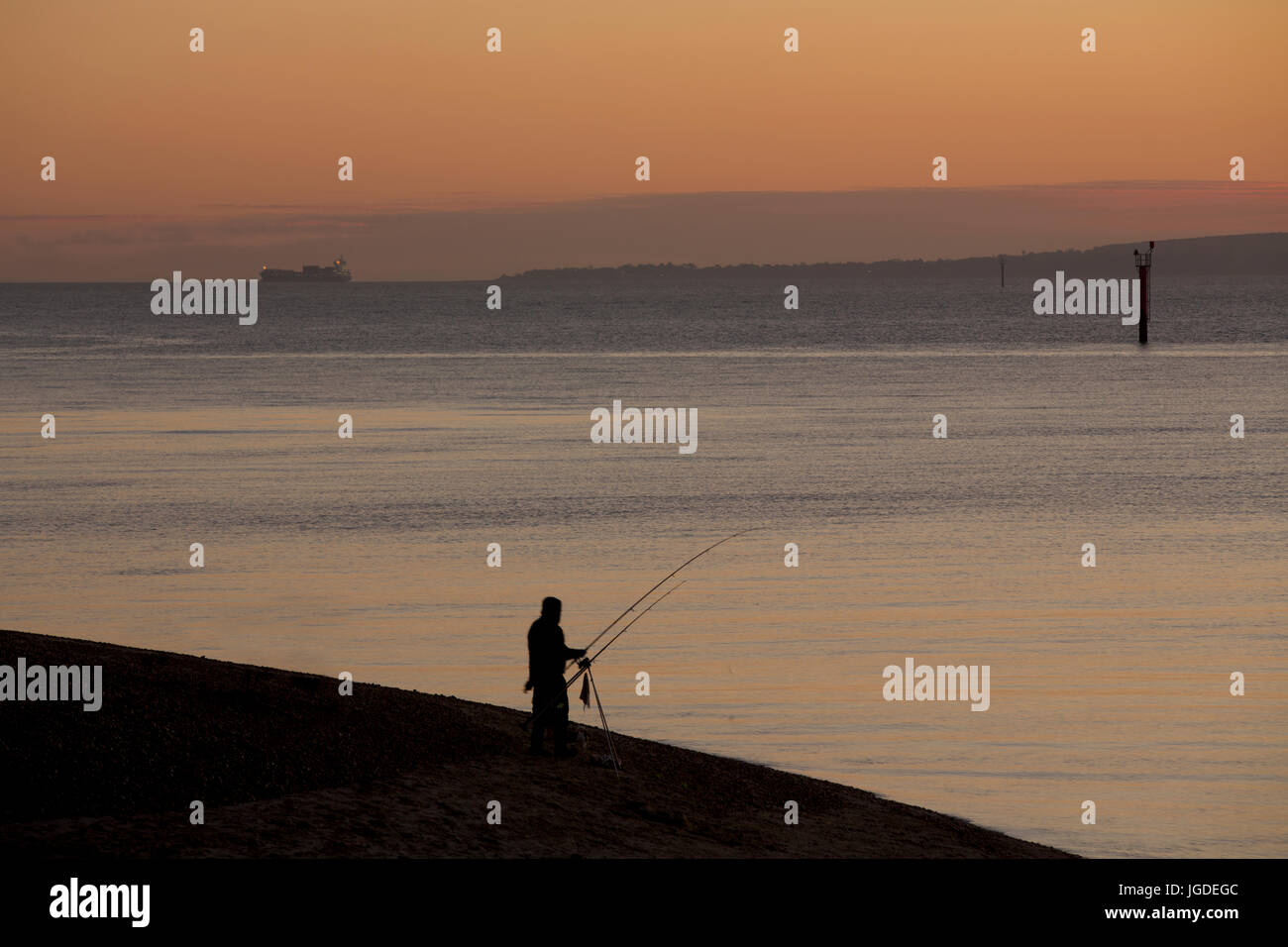 Silhouette Fischer angeln bei Sonnenuntergang an der Südküste von England. Orangefarbenen Himmel und ruhiger See auf Hayling Island. Idyllischer Weg, um einen Abend zu verbringen. Stockfoto