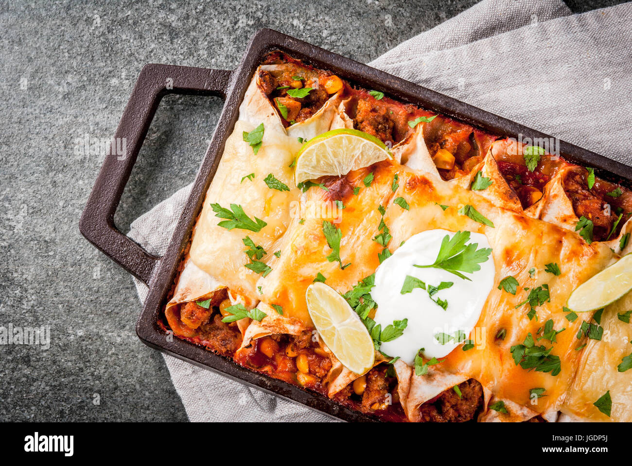 Mexikanisches Essen. Küche von Südamerika. Traditionelles Gericht der würzige Rindfleisch Enchiladas mit Mais, Bohnen, Tomaten. Auf ein Backblech, auf einem schwarzen Stein Hinterg Stockfoto