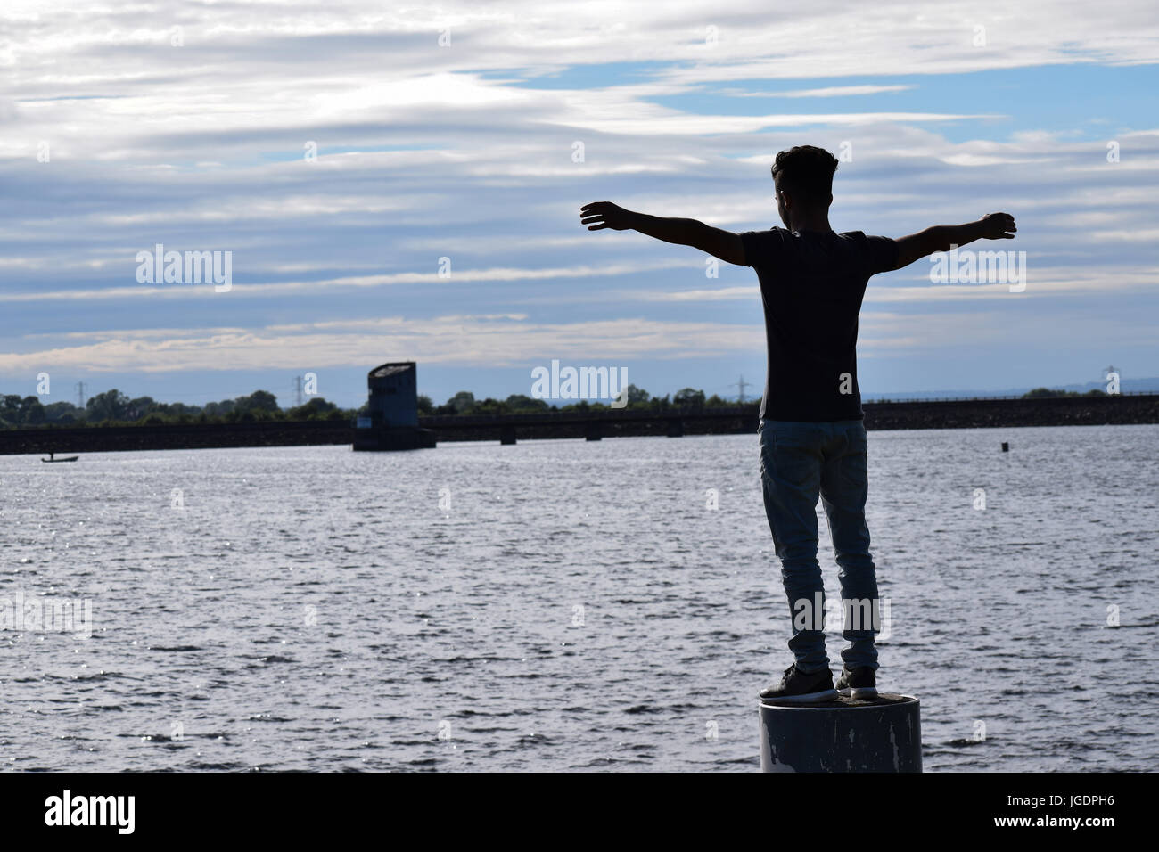 Kleiner Junge feiert Freiheit, Erfolg mit geöffneten Armen zum Himmel blickte glücklich und seine Leistungen in den Abend am Strand genießen. Stockfoto