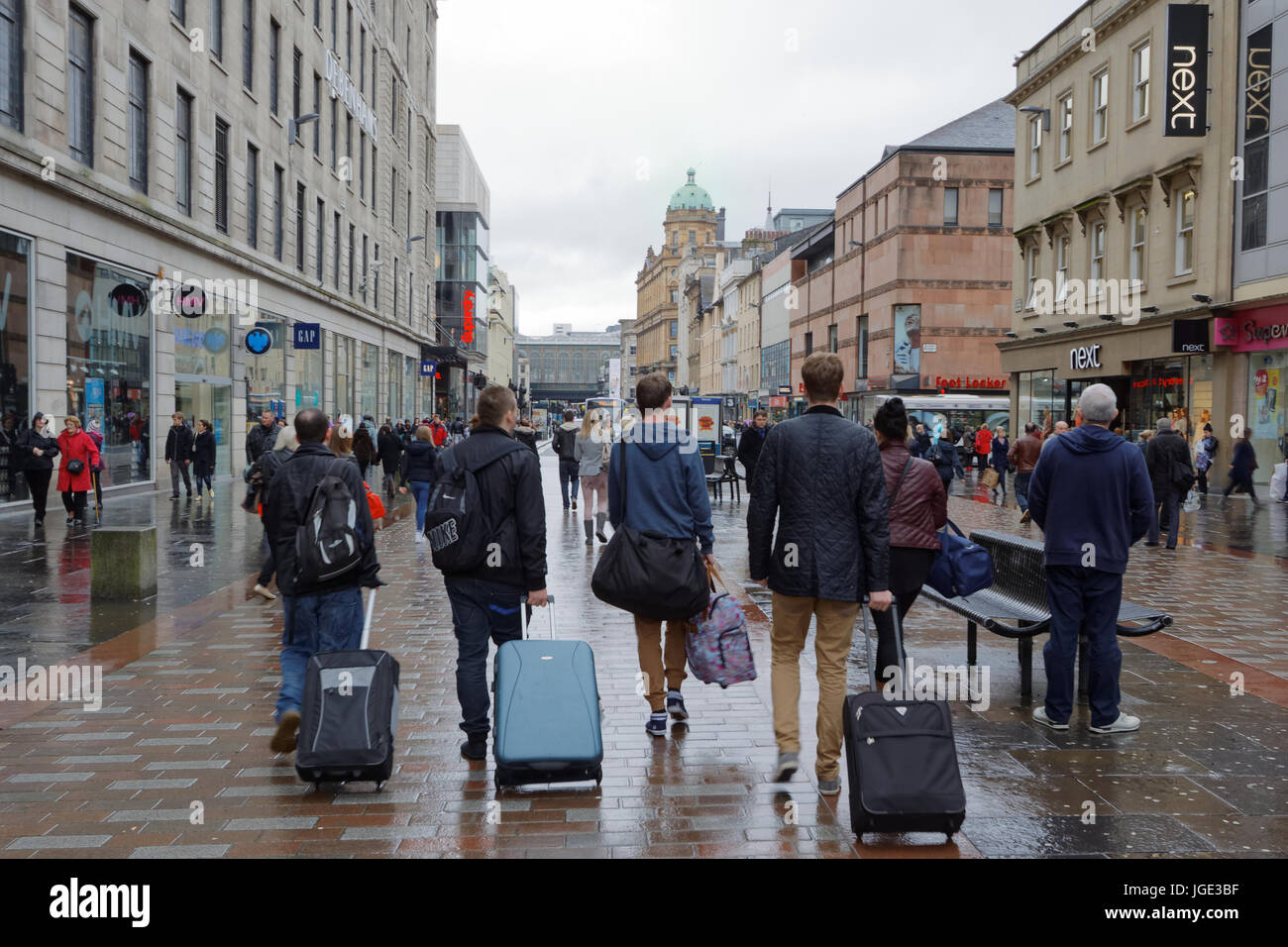 Glasgow Straße Touristen mit Gepäckwagen Argyle Street Glasgow Schottland nassen verregneten Oberfläche entlang Stockfoto