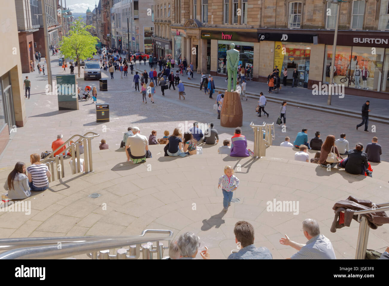 Touristen und Einheimische genießen das sonnige Wetter auf den Stufen der Sauchiehall Street in der Nähe von Donald Dewar-statue Stockfoto