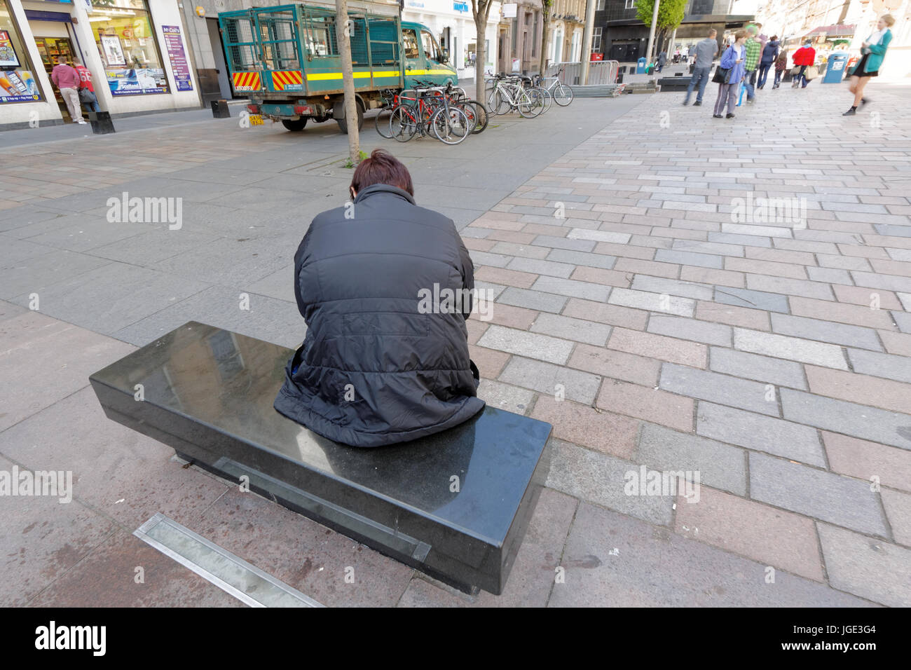 Depression und Isolation Person auf Bank allein schaukelte hin und her auf belebten Straße arbeitslos geistige Wohlfahrt Stockfoto
